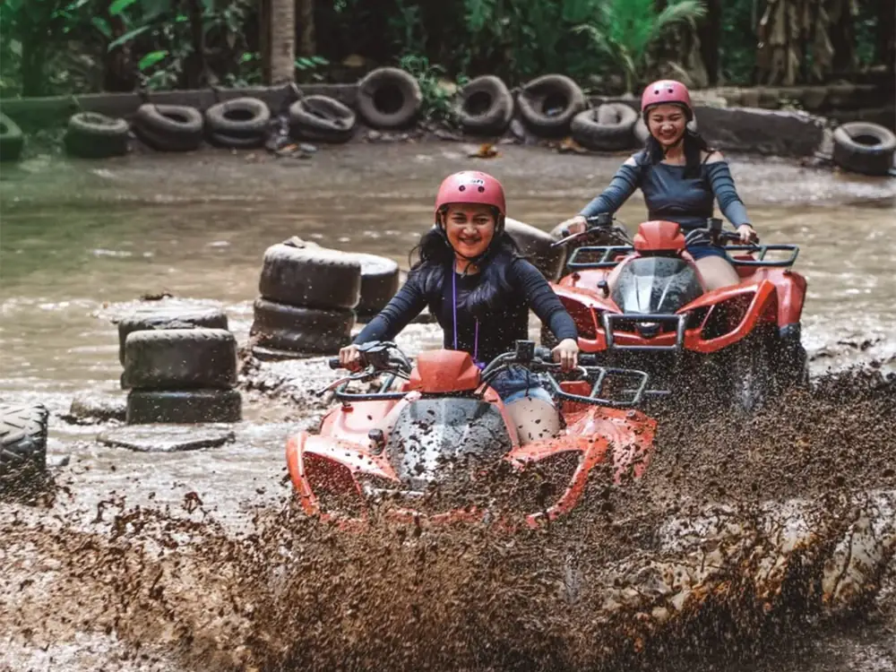 An ATV throwing up brown water while riding through a deep mud puddle