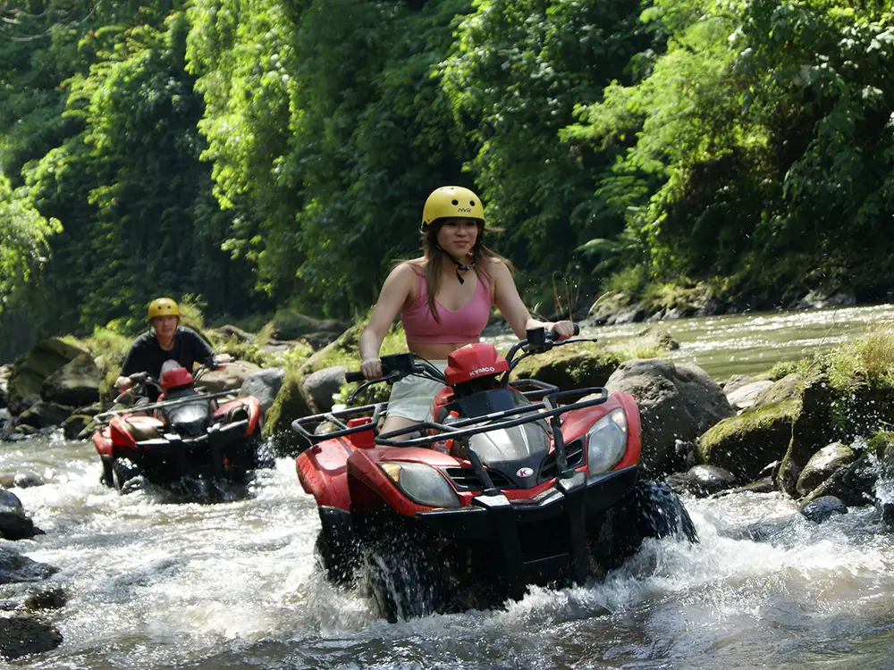 An ATV crossing a shallow river through jungle on a private track in Bali