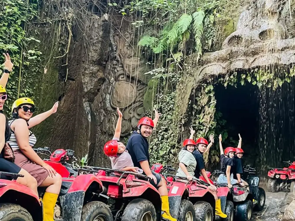 ATV riders passing through a Balinese village on a traditional village trail